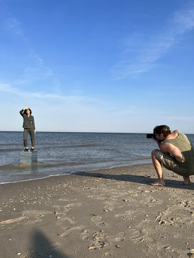 Photographer crouching on the beach shooting a model on a plinth in the water, flash by Kilian Amrehn