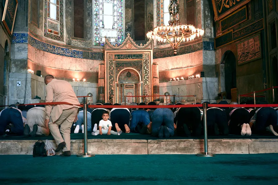 Worshippers praying before the mihrab of Hagia Sophia, a child looks back, Istanbul, flash by Kilian Amrehn