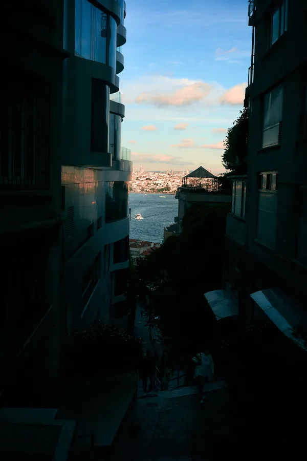 Narrow gap between buildings with a view of the water at dusk, Istanbul, flash by Kilian Amrehn