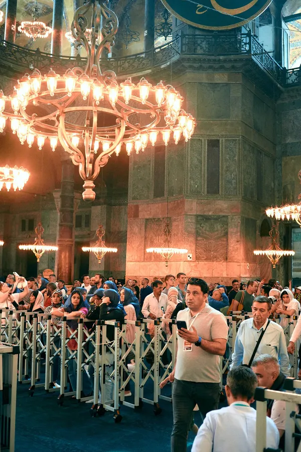 Crowd of visitors behind barriers under the chandeliers of Hagia Sophia, Istanbul, flash by Kilian Amrehn