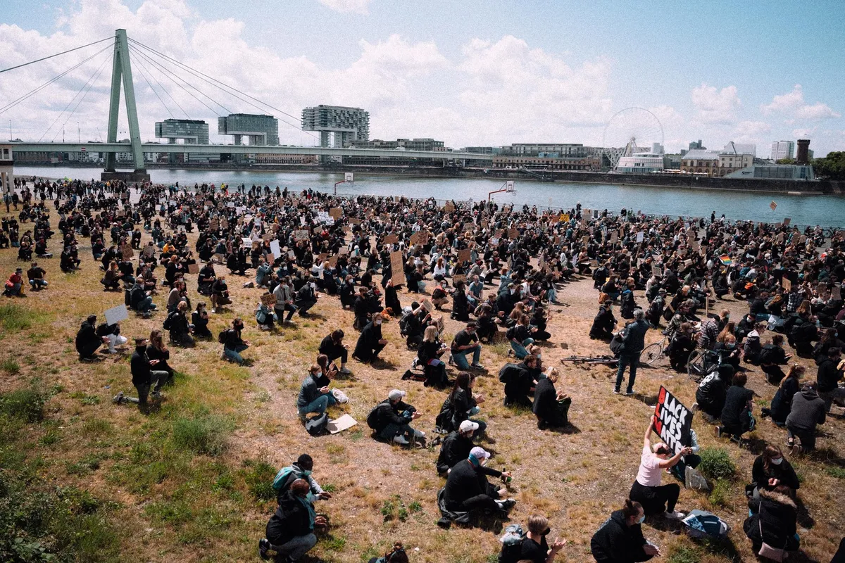 Tausende sitzen auf der Rheinwiese vor Severinsbrücke und Kranhäusern, Protestschilder, Black Lives Matter Köln 2020, Reportage von Kilian Amrehn