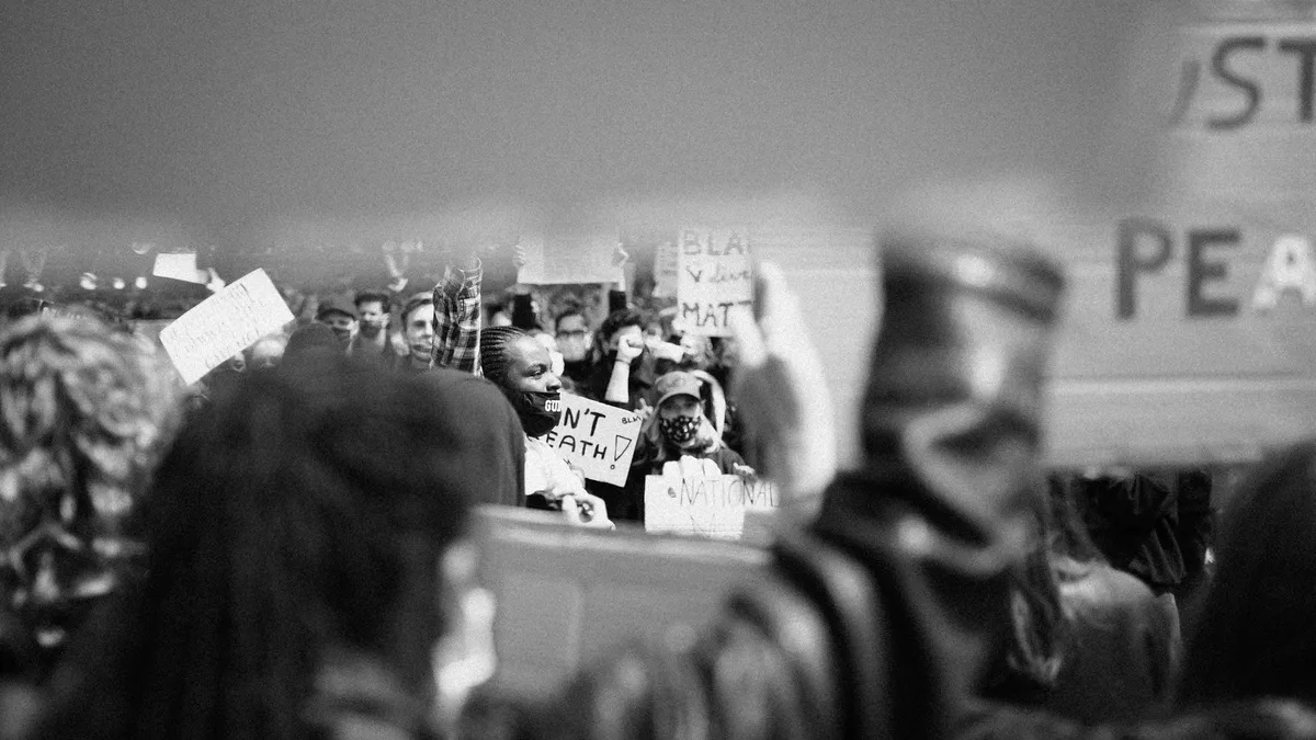 Demonstrierende mit Masken und Schildern, unscharfer Vordergrund mit Schild Peace, schwarzweiß, Black Lives Matter Köln 2020, Reportage von Kilian Amrehn