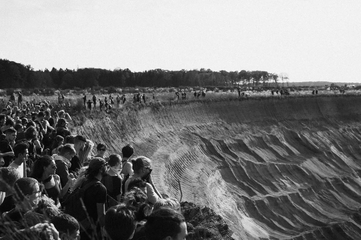 Menschenmenge steht dicht an der Abbruchkante des Tagebaus, Blick in die Grube, schwarzweiß, Hambacher Forst 2018, Reportage von Kilian Amrehn