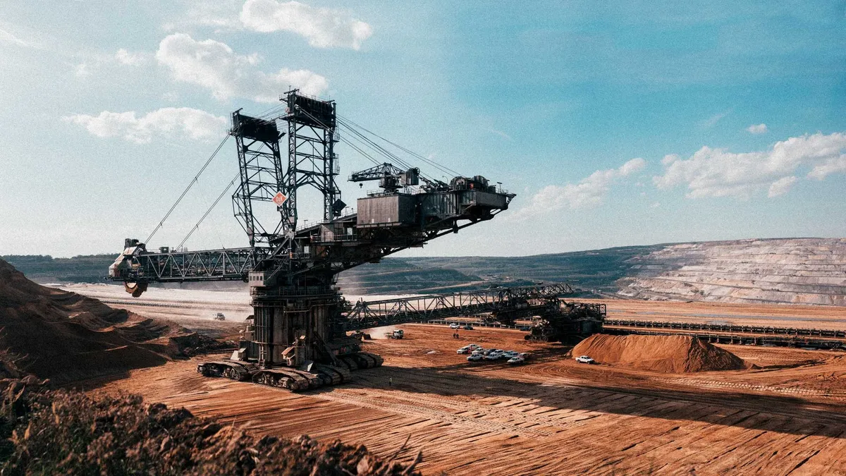 Schaufelradbagger auf rotbraunem Sand im Tagebau unter blauem Himmel mit Wolken, Hambacher Forst 2018, Reportage von Kilian Amrehn