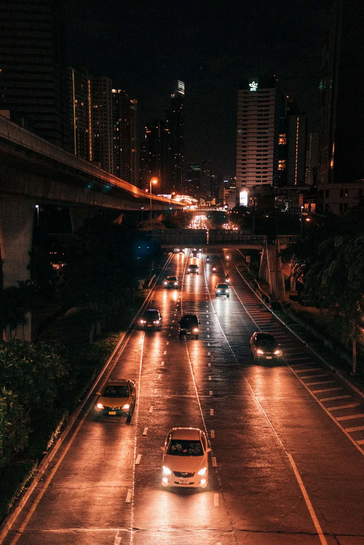 Mehrspurige Straße mit Autolichtern bei Nacht zwischen Hochhäusern und Hochbahn, Blick von oben, Thailand 2017, Reportage von Kilian Amrehn