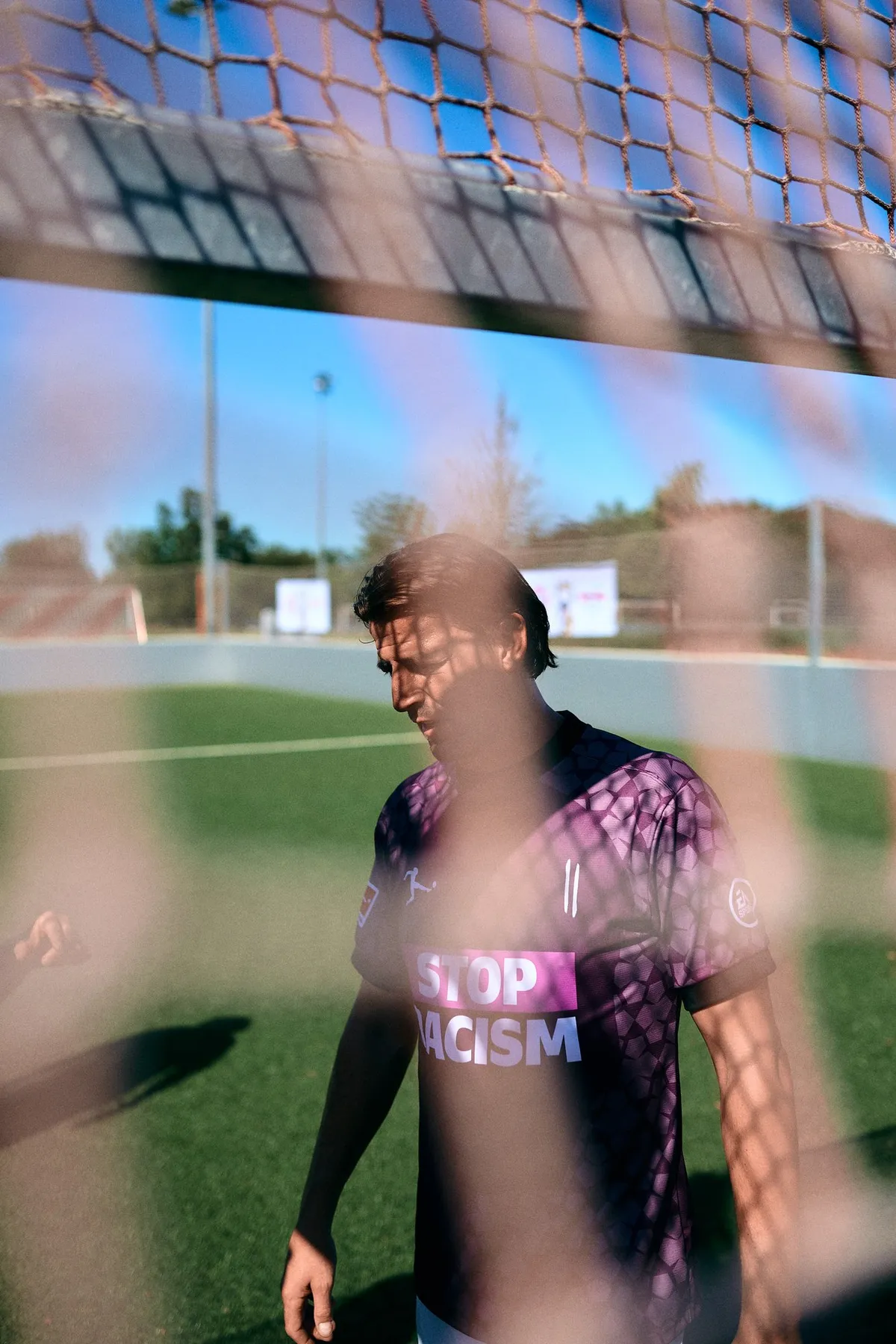 Bundesliga, player in a Stop Racism shirt photographed through the goal net, sunny training pitch, sports photography, photographed by Kilian Amrehn