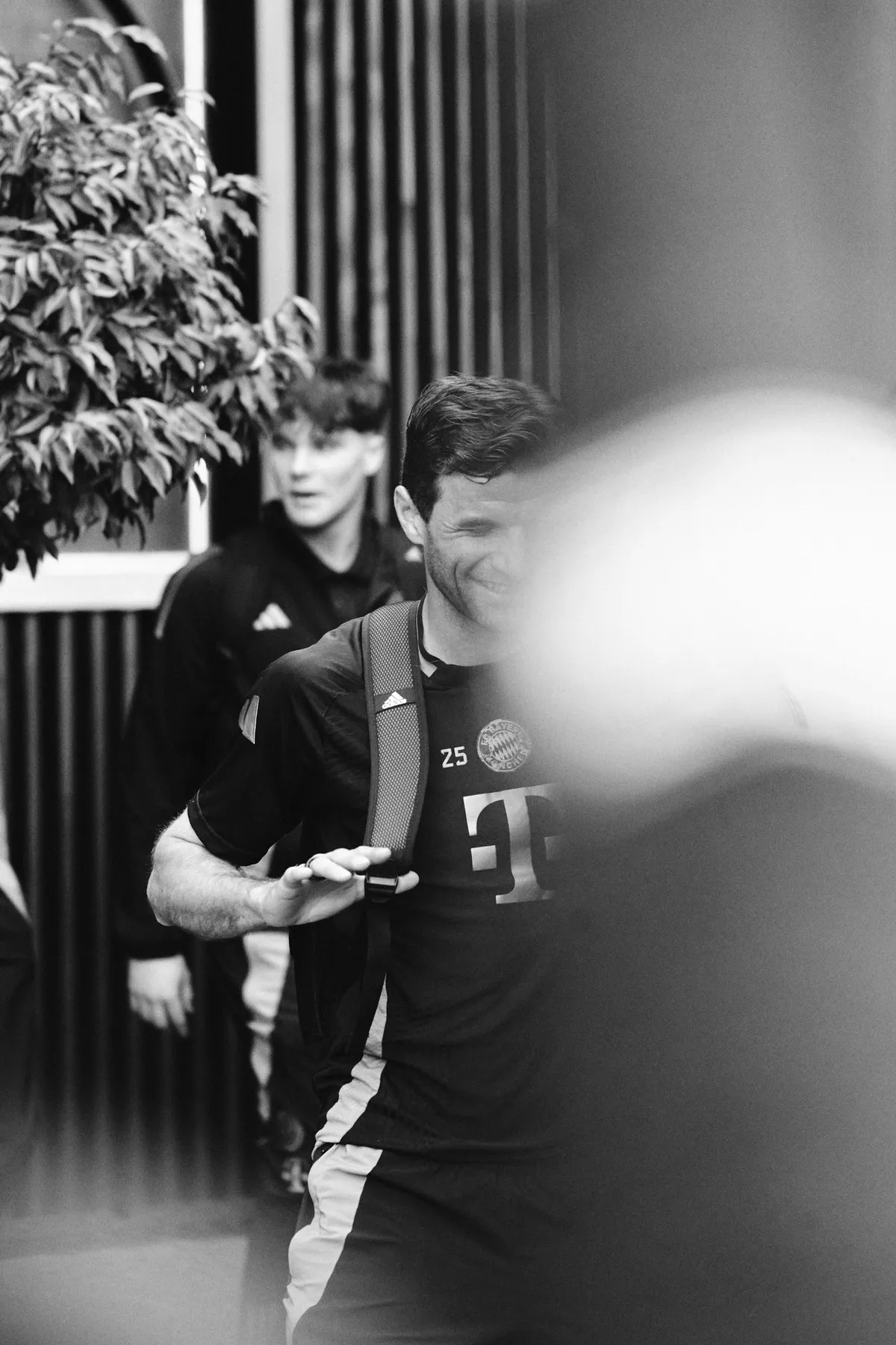 Bundesliga, smiling player in a training shirt walking through the players' tunnel, blurred foreground, black and white, sports photography, photographed by Kilian Amrehn