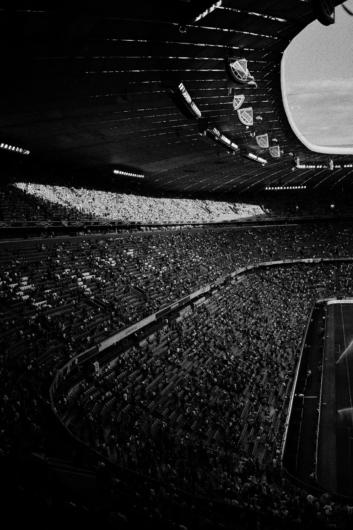 Bundesliga, steep stands and roof structure of a packed stadium seen from above, dark black and white, sports photography, photographed by Kilian Amrehn
