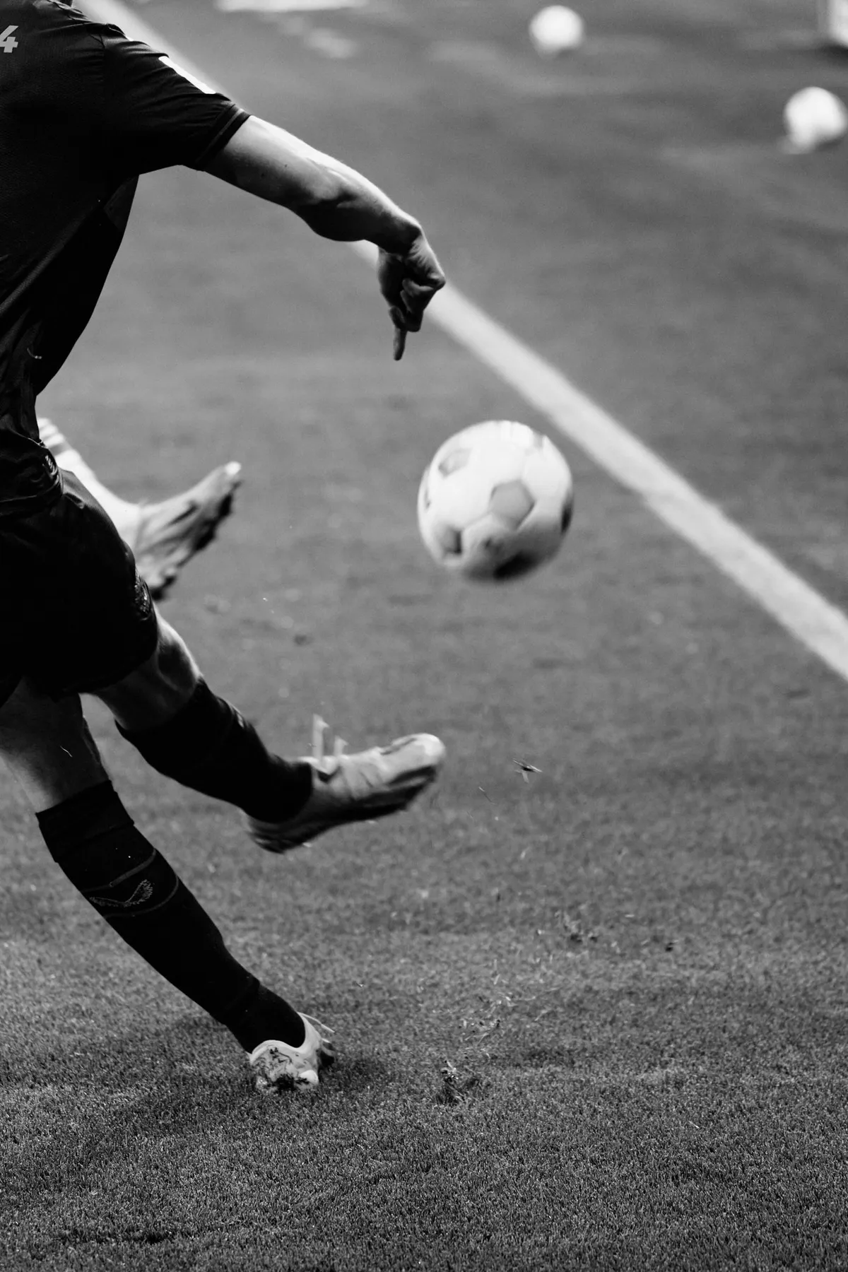 Bundesliga, corner kick up close with a boot striking the ball at the line, more balls behind, black and white, sports photography, photographed by Kilian Amrehn