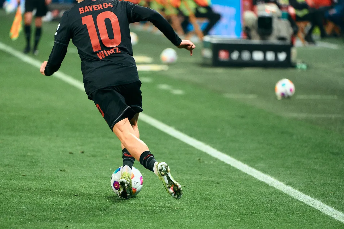 Bundesliga, Bayer 04 player number 10 dribbling along the touchline, green pitch in colour, sports photography, photographed by Kilian Amrehn