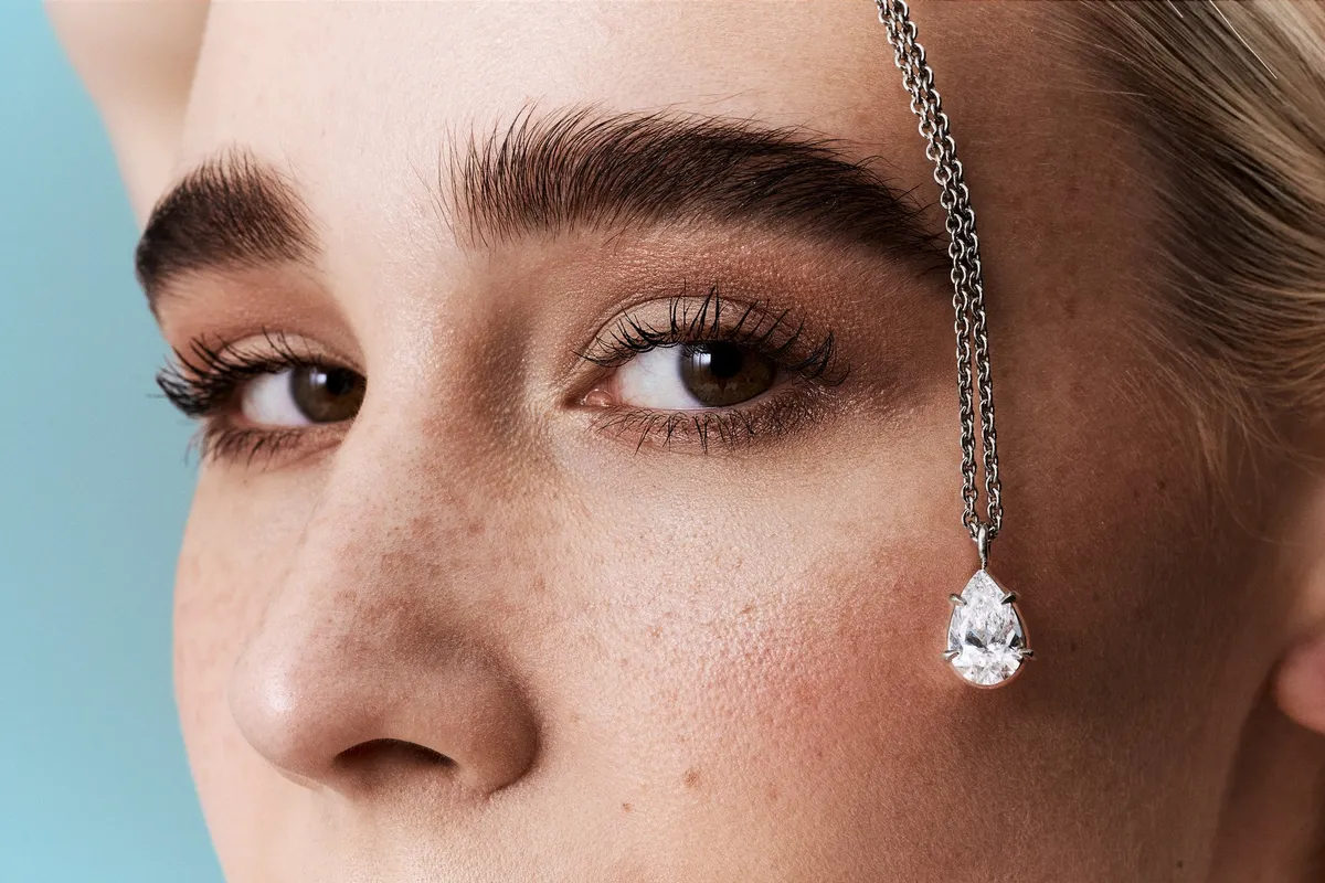 Monano, chain with a pear-shaped diamond pendant hanging across the face of a freckled model, jewellery campaign 2024, photographed by Kilian Amrehn
