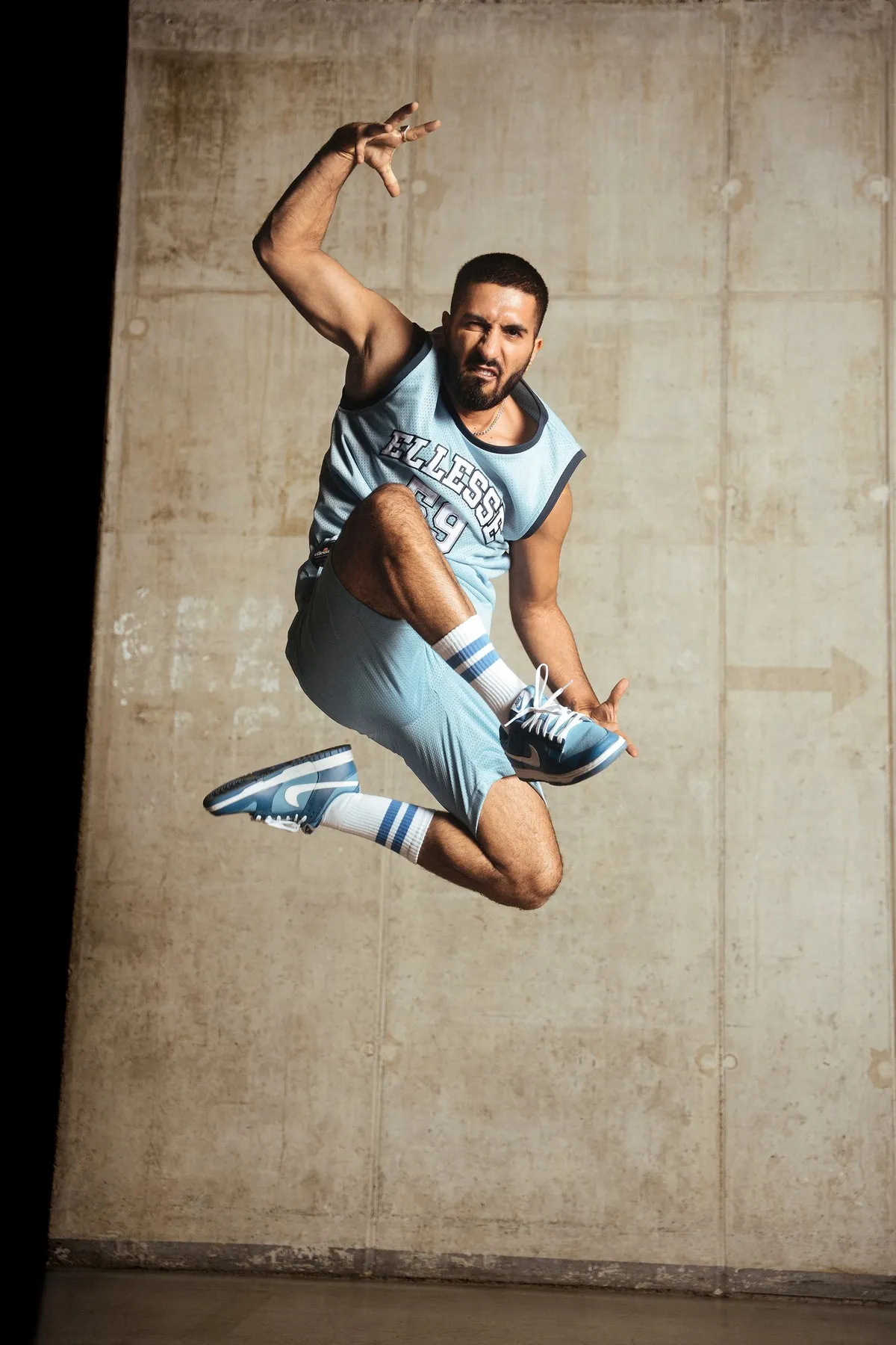 Peek & Cloppenburg x Ellesse, model leaping mid-air in a light blue Ellesse jersey and shorts against a concrete wall, campaign 2022, photographed by Kilian Amrehn