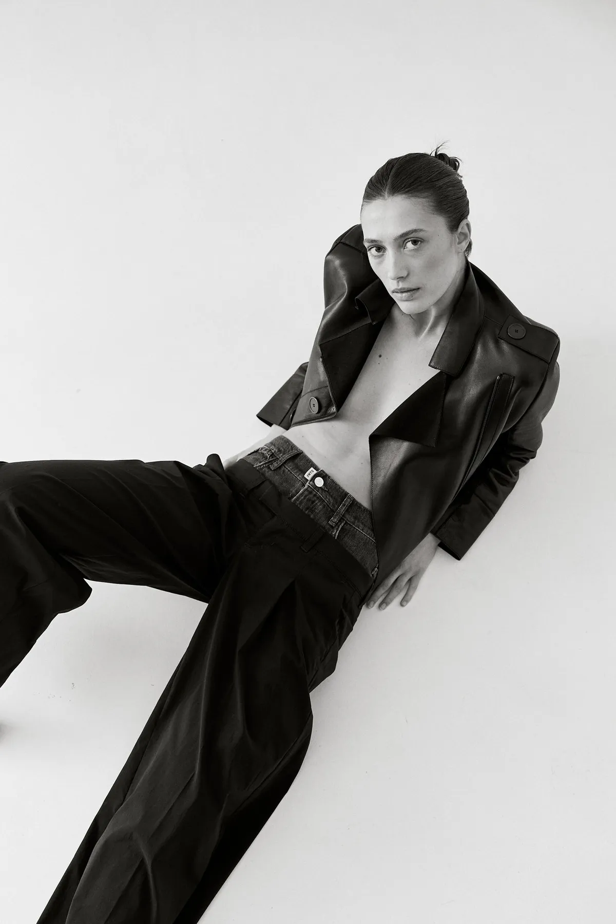 PNTS, model in a black leather jacket and wide dark trousers leaning back, black and white studio shot, campaign 2022, photographed by Kilian Amrehn