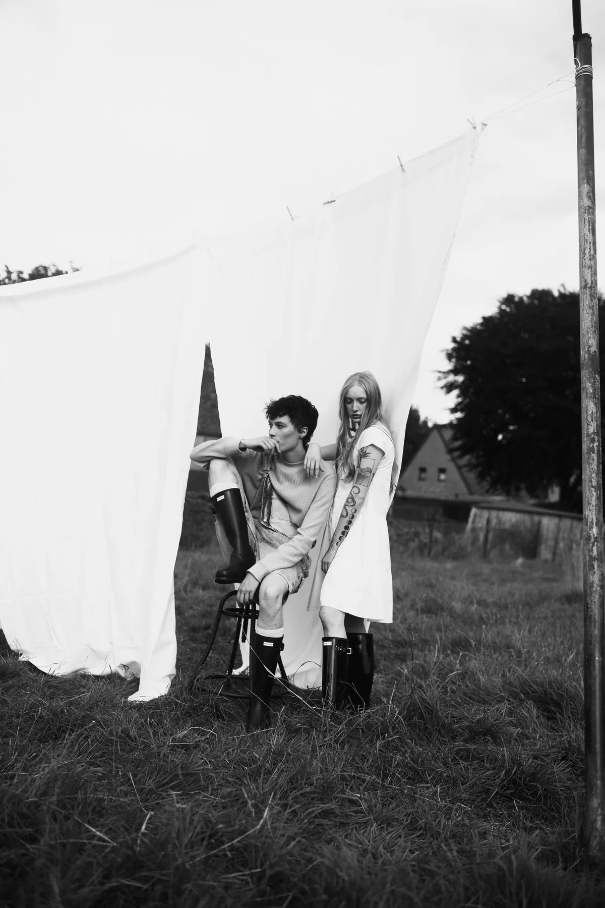 Rock Fairyland, two models in rubber boots in front of white sheets on a washing line in a field, black and white, editorial 2021, photographed by Kilian Amrehn