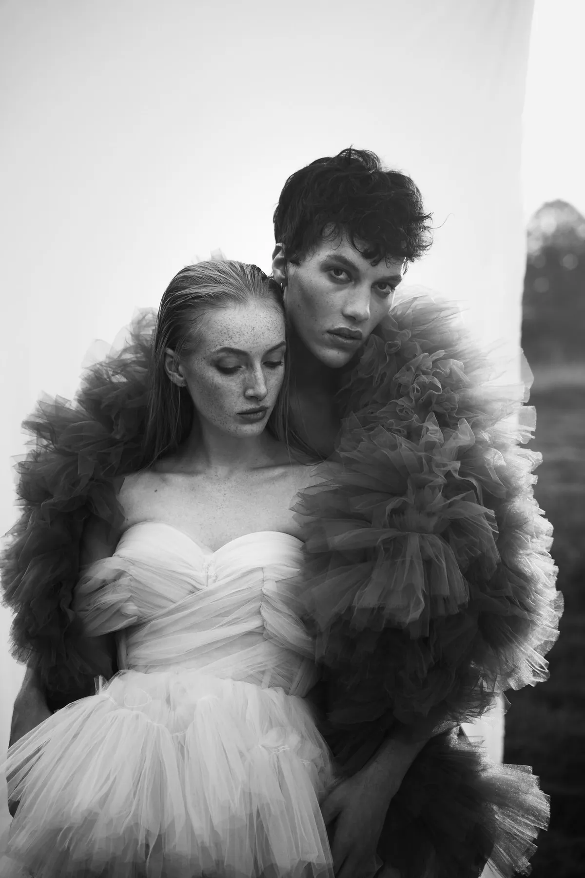 Rock Fairyland, model with dark curls embracing a model in a white tulle dress from behind, voluminous tulle in black and white, editorial 2021, photographed by Kilian Amrehn