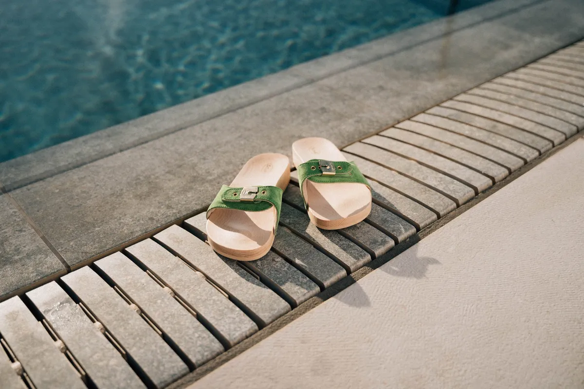 Scholl iconic, green wooden slides with buckle on a slatted pool edge, sunlight and water, campaign Fuerteventura 2021, photographed by Kilian Amrehn