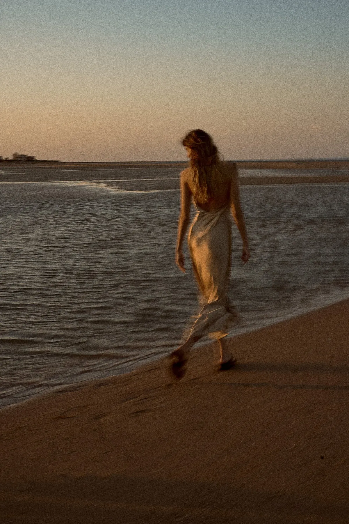 Scholl Comfort, model in a satin dress walking through shallow water on the beach at sunset, Egypt 2023, photographed by Kilian Amrehn