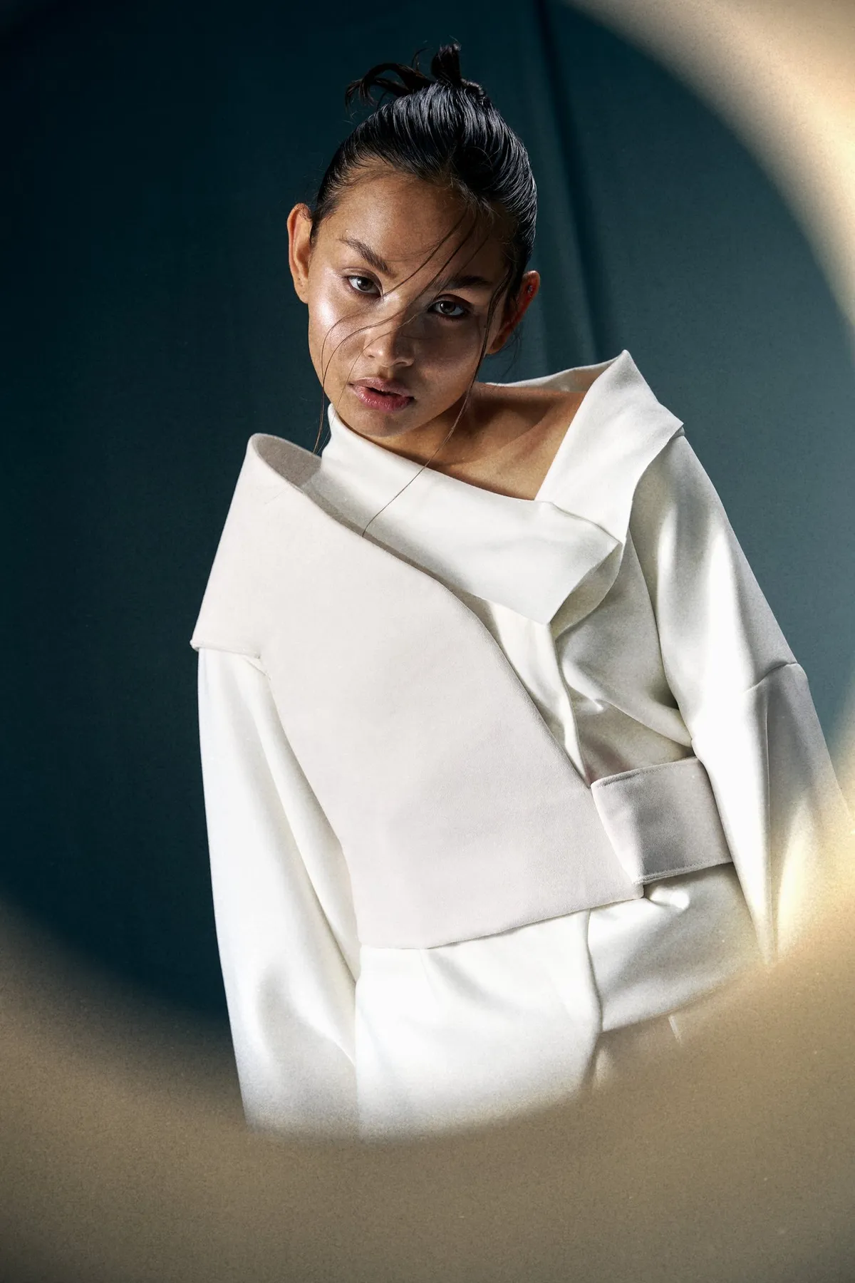 JEREMIAH Silent Escape, model with a bun in a white oversized jacket with wide collar, circular framing against teal, campaign 2024, photographed by Kilian Amrehn