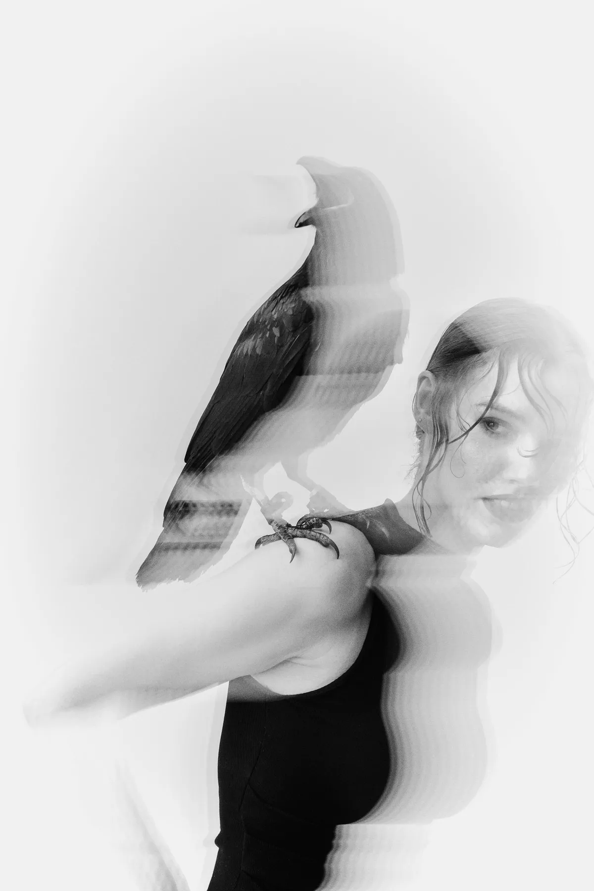 Untamed, model with a raven on her shoulder in a blurred multiple exposure, motion blur in black and white, editorial 2024, photographed by Kilian Amrehn