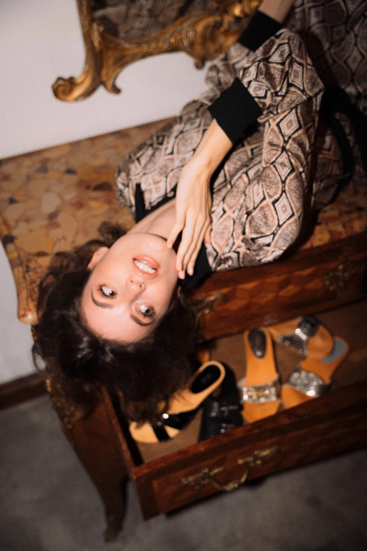 The Wants, model lying upside down on a dresser with an open drawer full of clogs, patterned dress in colour, campaign 2020, photographed by Kilian Amrehn