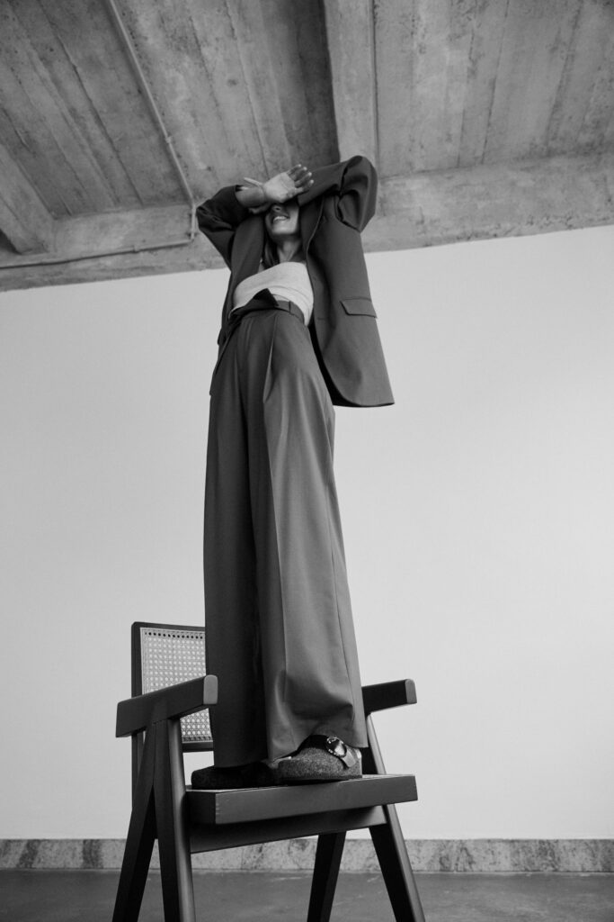Schwarz-Weiß Shooting von einer Frau die auf einem Stuhl steht