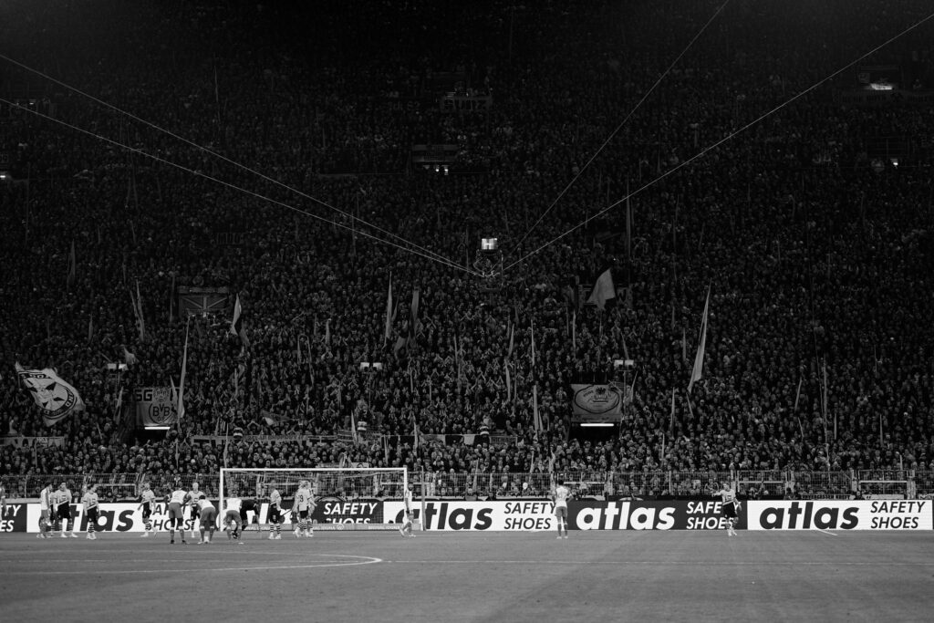 Schwarz-Weiß Foto von der Zuschauertribüne bei einem Fußballspiel