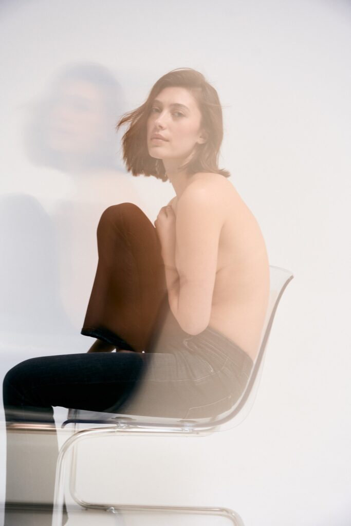 Foto von einer weiblichen Person sitzend auf einem Stuhl Oberkörperfrei