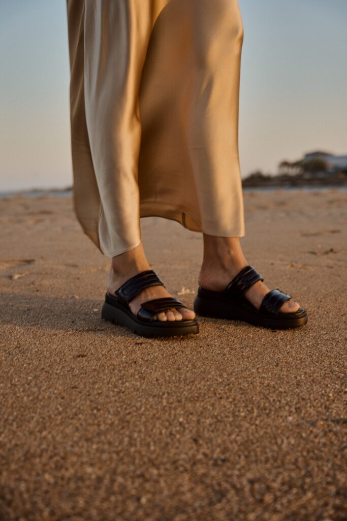 Foto von einem Model am Strand mit Sandalen