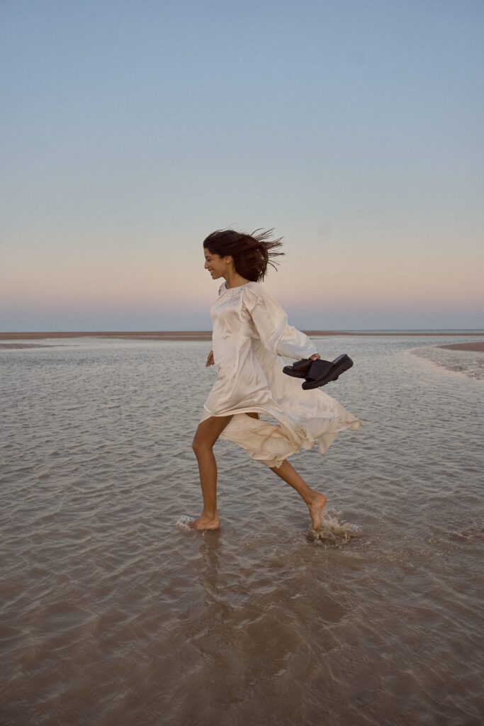 Fotoshooting von einem Model am Strand im seichten Wasser