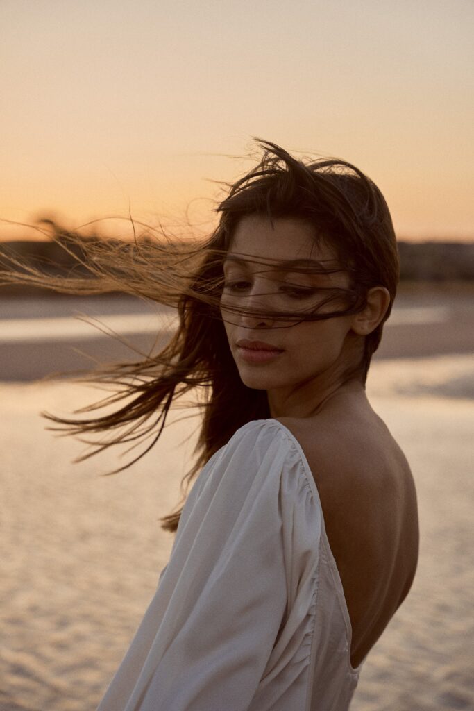 Foto von einem Model am Strand mit Haaren im Wind