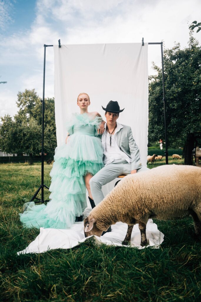 Fashionshooting von zwei Personen auf einer Weide mit Schafen