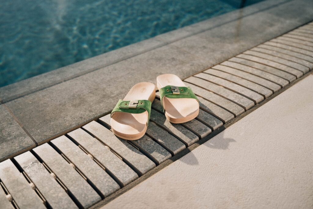 Foto von zwei Sandalen am Rande eines Pools