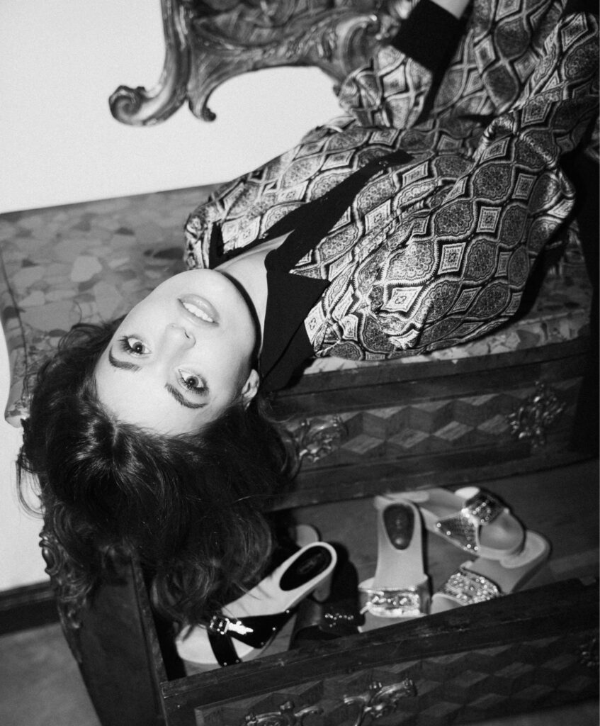 Schwarz-Weiß Foto von einer Frau liegend auf einem Schuhschrank